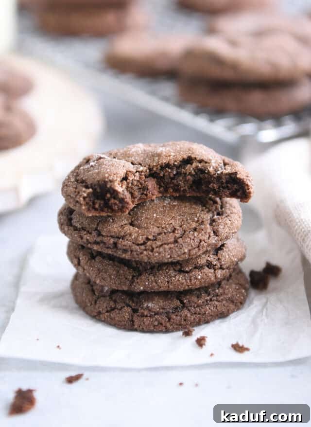 Pillowy Chocolate Ginger Molasses Chews 7 Bite taken out of chocolate ginger molasses cookie on stack of three whole cookies.