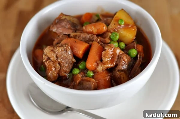 Slow Cooked Hearty Beef Stew 2 A beautiful white bowl filled with hearty slow cooker beef stew, featuring tender beef chunks, carrots, and potatoes in a rich gravy.