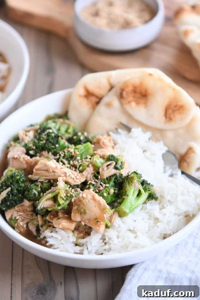 Effortless Chinese Chicken Broccoli Stir-Fry 2 Naan bread in white bowl with rice, chicken, broccoli and brown sauce, garnished with sesame seeds.