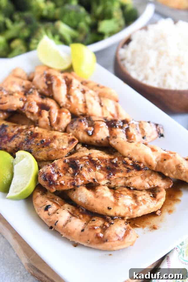 Tropical Ginger-Lime Chicken Tenders with Coconut Rice 2 White platter with spiced chicken tenders and fresh lime wedges on wood board.