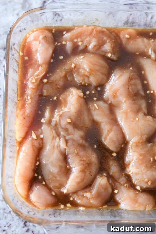 Tropical Ginger-Lime Chicken Tenders with Coconut Rice 4 Raw chicken tenders in glass baking dish with marinade poured over the top.