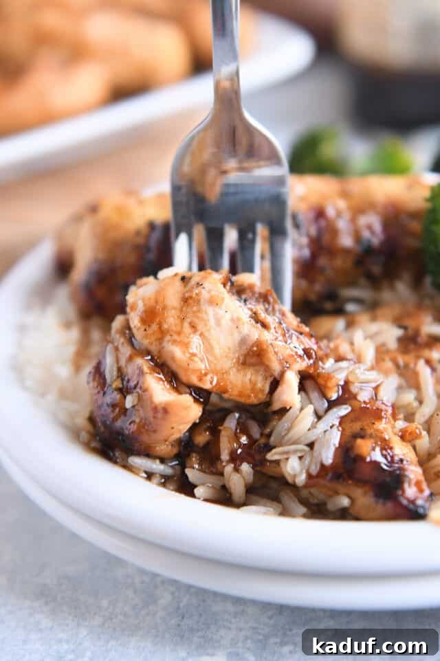Tropical Ginger-Lime Chicken Tenders with Coconut Rice 8 Fork with bite of saucy chicken tenders and white rice on white plate.