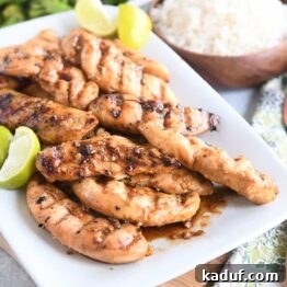 white platter with saucy, spiced chicken tenders and fresh lime wedges