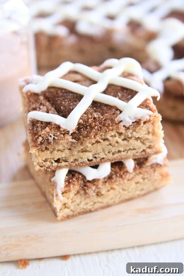 Cinnamon Roll Blondie Bars 2 Two cinnamon roll blondies stacked on each other on wood cutting board.