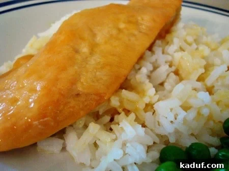 Honey Mustard Chicken Delights 2 Piece of honey mustard chicken on a bed of white rice, garnished with fresh herbs.