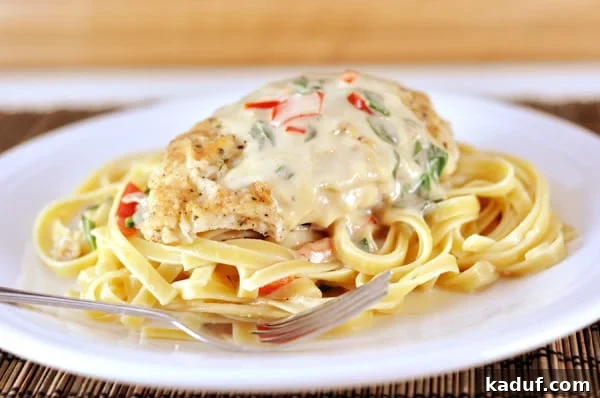 Olive Garden Style Tuscan Garlic Chicken 2 A white plate with cooked fettuccine, breaded chicken, and a pepper cream sauce. This dish is a copycat of Olive Garden's Tuscan Garlic Chicken, offering tender chicken and creamy sauce.