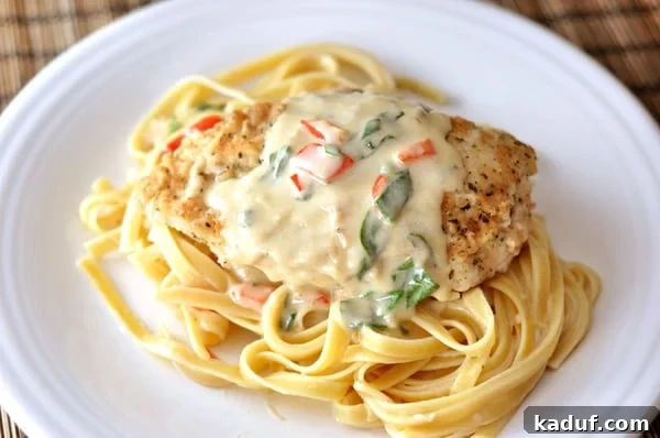 Olive Garden Style Tuscan Garlic Chicken 3 Top-down view of a white plate featuring cooked fettuccine, a perfectly breaded chicken breast, and a rich pepper cream sauce. This Olive Garden copycat is a delicious and satisfying meal.