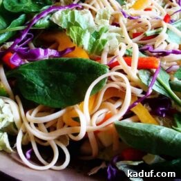 Delicious Asian Noodle Salad in a white bowl, garnished with fresh herbs and bell peppers.