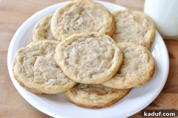 Buttery Toffee Crunch Cookies 4 A top-down view of a white ceramic plate filled with golden-brown, toffee-studded cookies, arranged neatly.