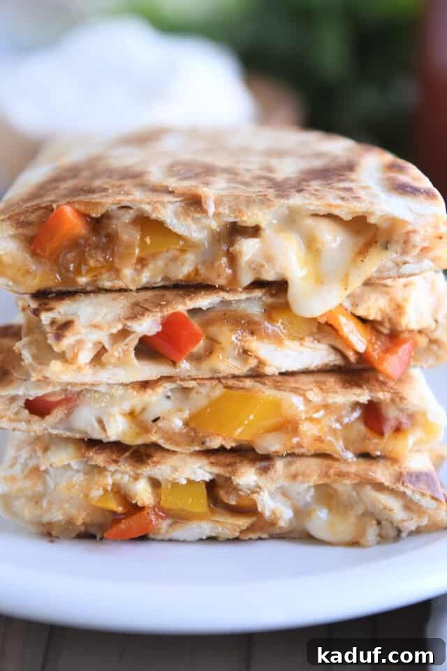 Irresistible Chicken Quesadillas 2 Four golden-brown chicken quesadillas, perfectly stacked and ready to serve on a white plate, highlighting their crispy texture and delicious filling.