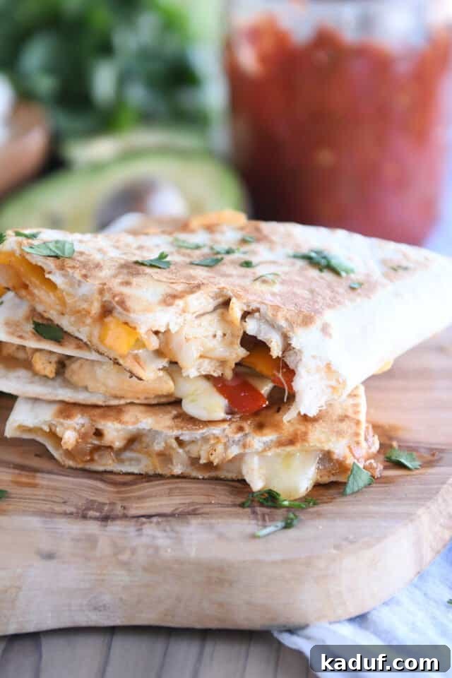 Irresistible Chicken Quesadillas 8 Three perfectly stacked triangle-cut chicken quesadillas on a rustic wooden board, ready to be enjoyed.