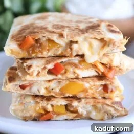 Irresistible Chicken Quesadillas 9 Four chicken quesadilla triangles stacked on a white plate, showcasing their golden crust and savory filling.