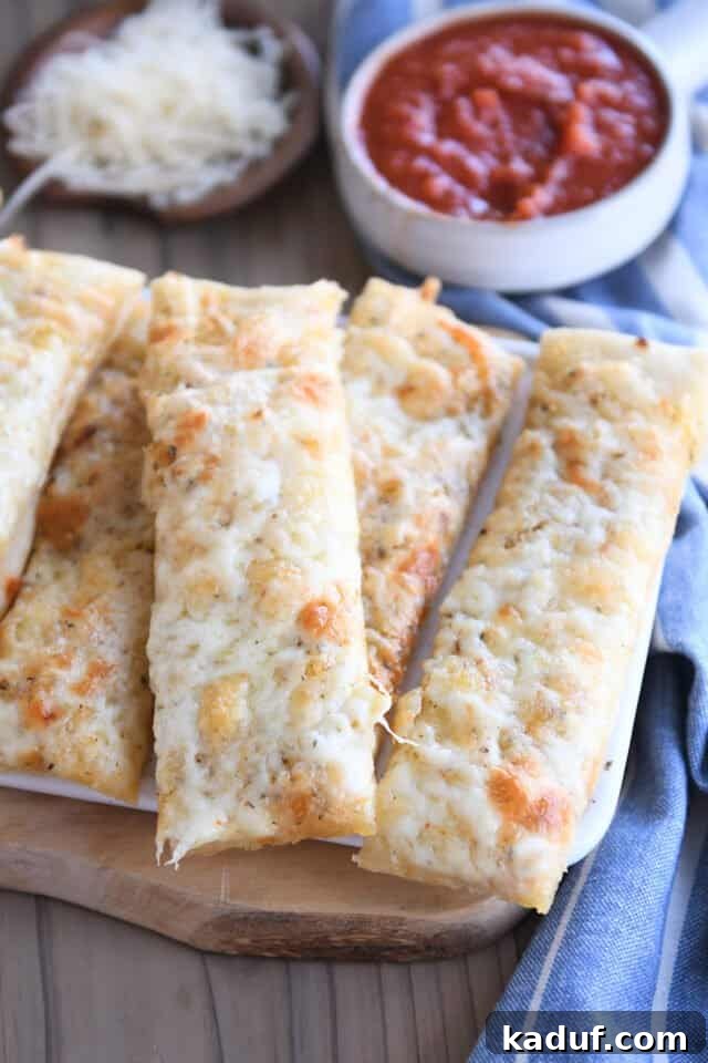Golden Cheesy Breadsticks 8 Four cheesy breadsticks arranged on a rustic wood cutting board, showcasing their golden-brown edges and melted cheese.