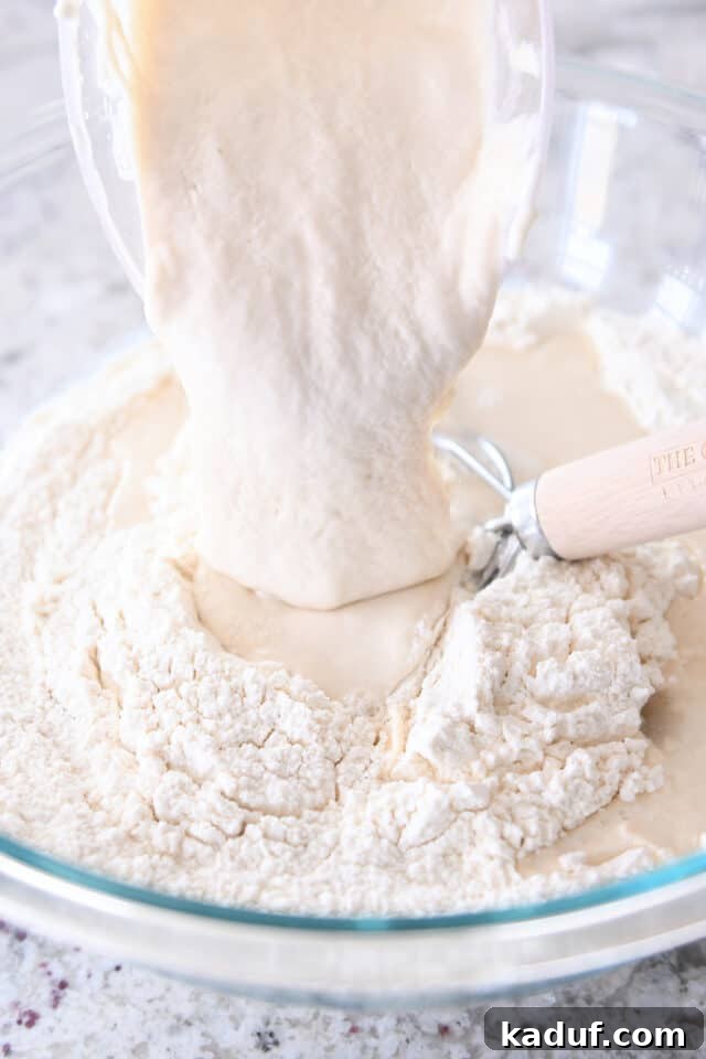 Effortless Rustic Sourdough Loaf 4 Pouring in thick sourdough discard into a bowl with dry flour ingredients, a key step for making no-knead bread.