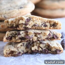 three half chocolate chip cookies stacked on each other on white parchment paper
