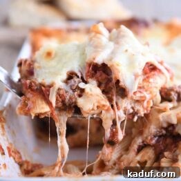 scooping serving of easy cheesy weeknight pasta bake out of white 9X13-inch pan