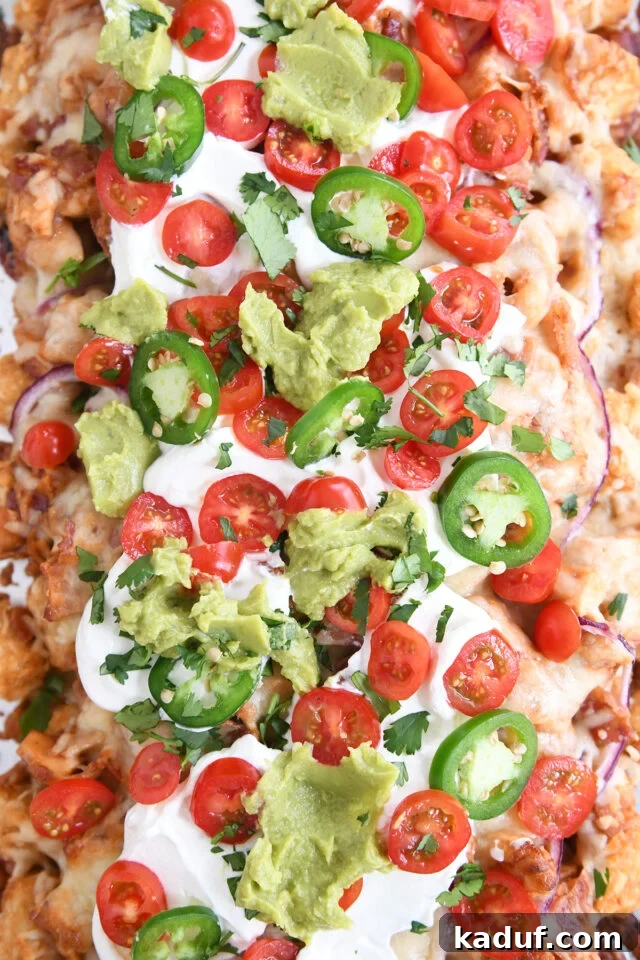 Ultimate BBQ Chicken Totchos 2 Close up top down view of bbq chicken totchos with sour cream, tomatoes and guacamole.