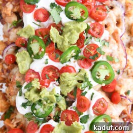 close up top down view of bbq chicken totchos with sour cream, tomatoes and guacamole
