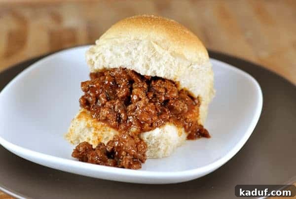 Seriously Delicious Sloppy Joes 7 A perfectly prepared sloppy joe served on a roll, presented elegantly on a white plate, ready to be enjoyed.