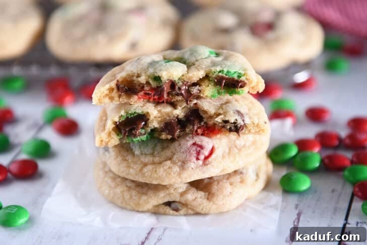 Festive M&M Holiday Cookies 2 Close-up of two M&M Christmas cookies with melted chocolate chips and a broken cookie revealing its soft interior.