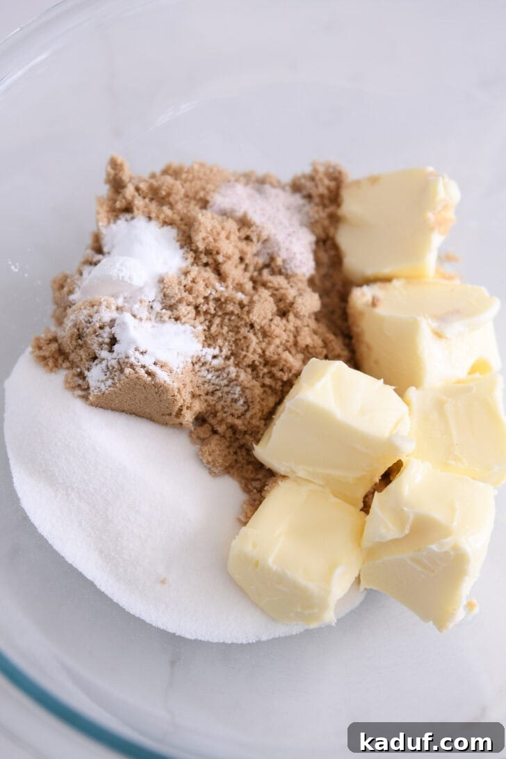 Festive M&M Holiday Cookies 3 Image of a glass bowl with butter, brown sugar, and granulated sugar creamed together.