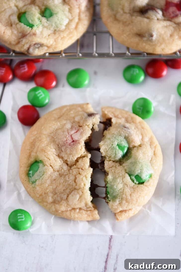 Festive M&M Holiday Cookies 7 Close-up of a broken M&M Christmas cookie revealing its soft and chewy interior with melted chocolate chips.