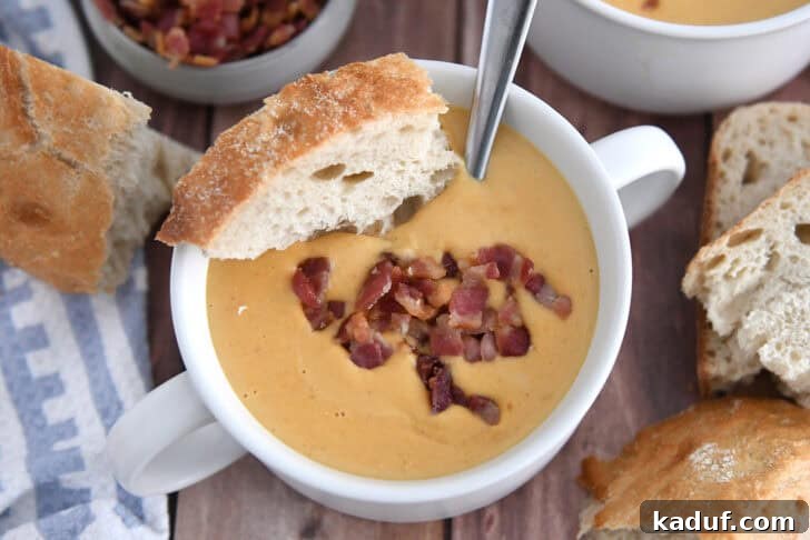 The Ultimate Butternut Squash Soup Experience 2 Creamy roasted butternut squash soup in a white bowl, garnished with crusty bread and crispy bacon pieces.