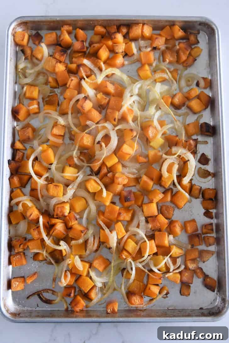 The Ultimate Butternut Squash Soup Experience 3 Butternut squash and onions roasting on a sheet pan.