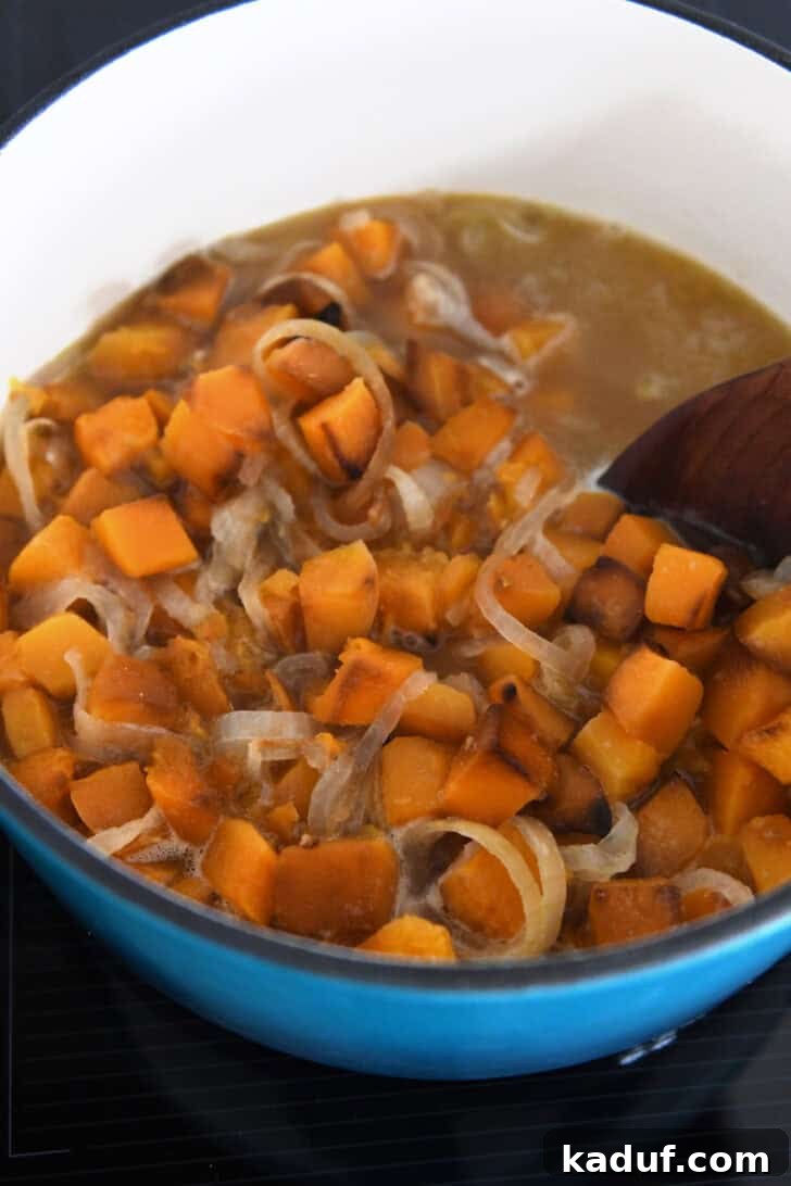 The Ultimate Butternut Squash Soup Experience 4 Combining the roasted vegetables with broth in a soup pot.