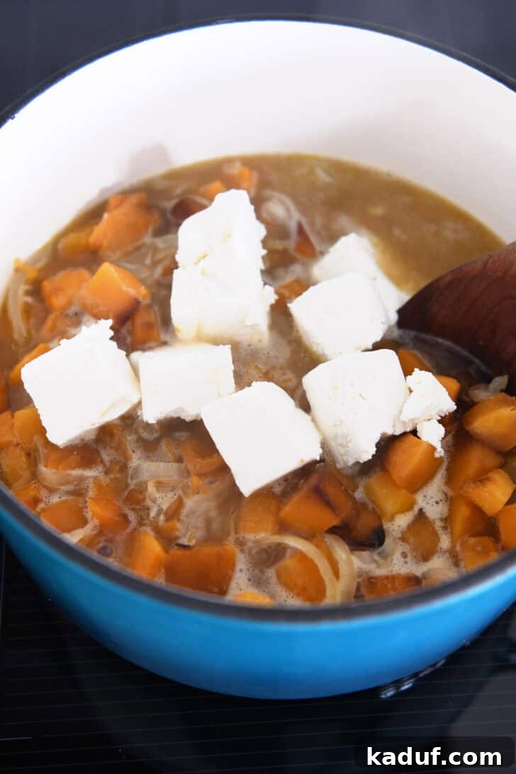 The Ultimate Butternut Squash Soup Experience 5 Adding cream cheese to the soup for creaminess.