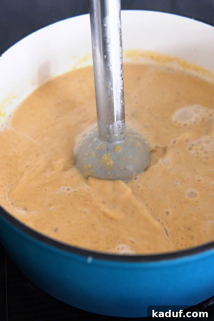 The Ultimate Butternut Squash Soup Experience 6 Using an immersion blender to puree the soup.