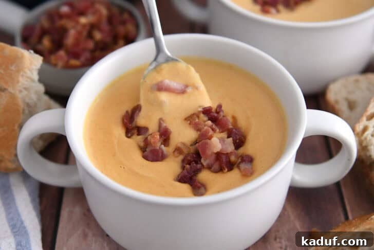 The Ultimate Butternut Squash Soup Experience 9 Butternut squash soup being spooned in white bowl topped with bacon.