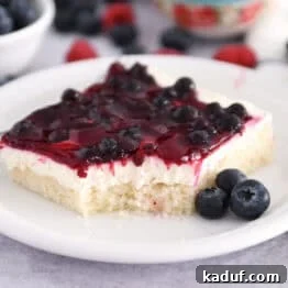 Grandma's Secret Sheet Cake Recipe 11 Square of white sheet cake topped with cream cheese layer and fruit topping on white plate with fresh blueberries.