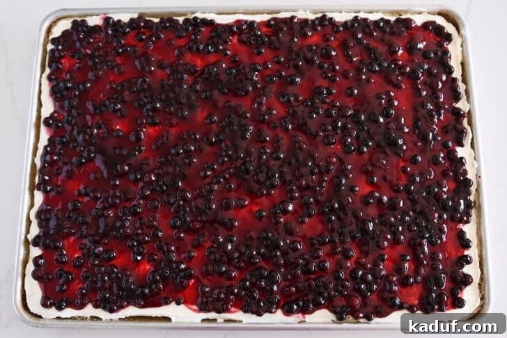 Grandma's Secret Sheet Cake Recipe 9 White sheet cake in a half sheet pan topped with the cream cheese frosting and huckleberry fruit topping.