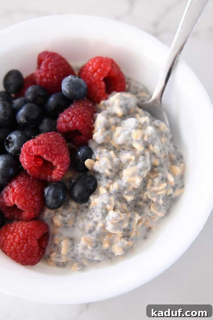 Best Ever Overnight Chia Oats 2 Overnight chia oats in a white bowl with blueberries and raspberries