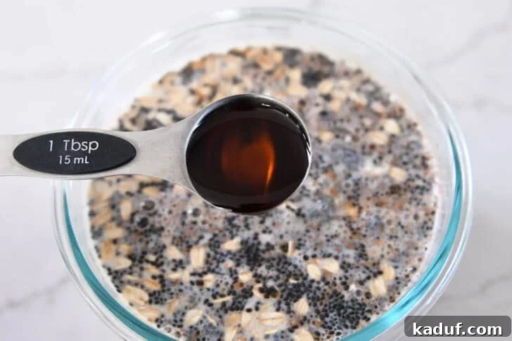 Best Ever Overnight Chia Oats 7 Pouring tablespoon of pure maple syrup into overnight chia oats