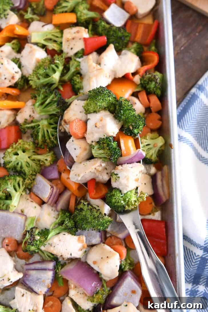 Sweet & Sticky Sheet Pan Chicken Dinner 2 Top down view of serving spoon with cooked chicken, broccoli, carrots, bell peppers and red onions.