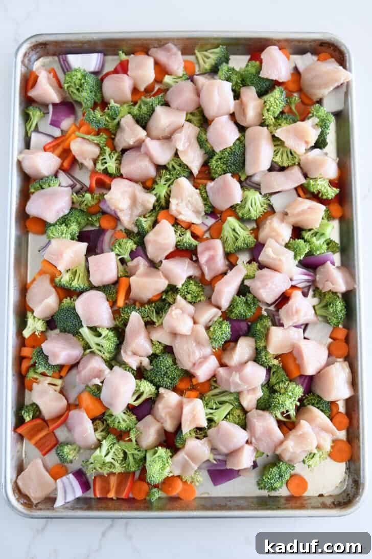 Sweet & Sticky Sheet Pan Chicken Dinner 4 Sheet pan with red onions, carrots, bell peppers, chicken, and broccoli.