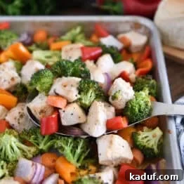 Sweet & Sticky Sheet Pan Chicken Dinner 7 Serving spoon with cooked chicken, broccoli, carrots, bell peppers and red onions.