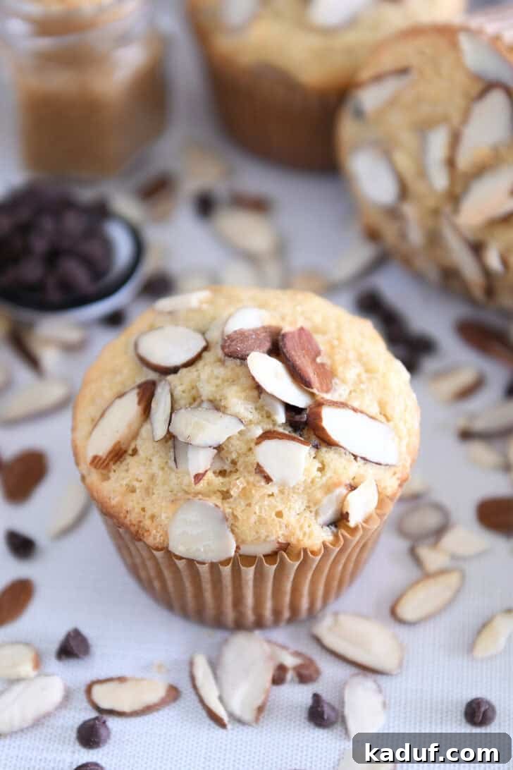 Decadent Almond Coconut Chocolate Chip Muffins 2 Almond coconut chocolate chip muffin on brown paper muffin liner.