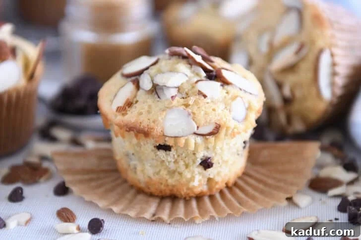 Decadent Almond Coconut Chocolate Chip Muffins 8 Unwrapped almond coconut chocolate chip muffin on brown paper muffin liner.