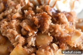 Serving of caramel apple crisp on gray plate with scoop of ice cream.