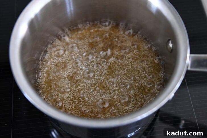 Sugar and water simmering in saucepan and turning golden brown in color.
