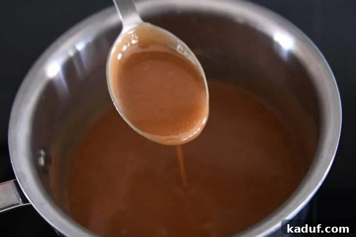 Spoon drizzling hot caramel sauce into saucepan.