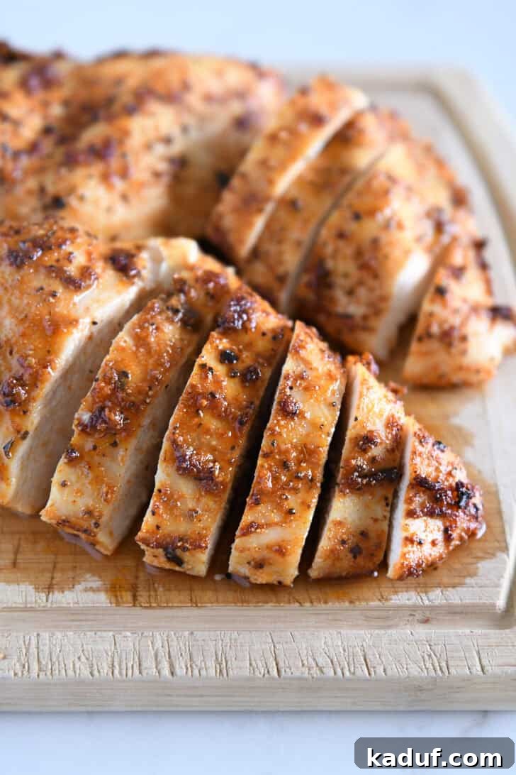 Sliced cooked chicken breasts on wood cutting board.