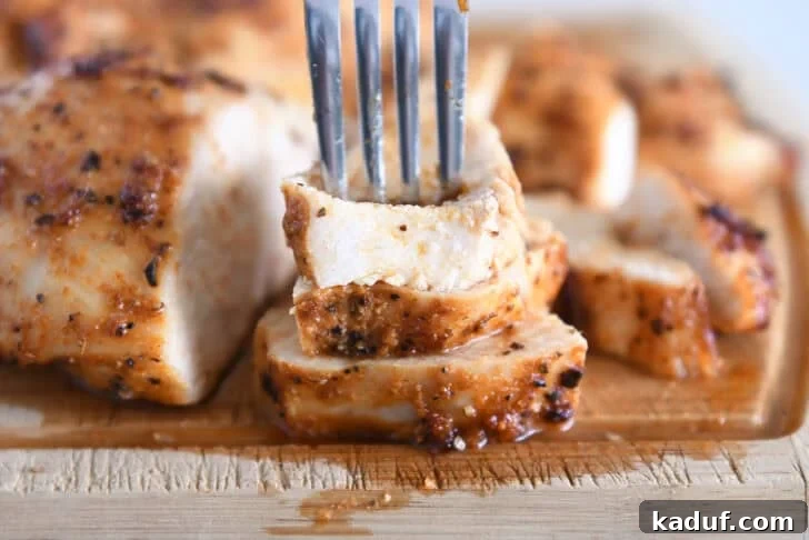 Fork piercing three pieces of air fryer chicken breasts.