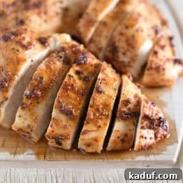 Sliced cooked chicken breasts on wood cutting board.