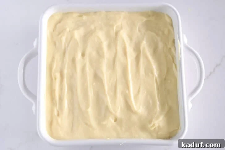 Homemade Banana Pudding from Scratch: Creamy Classic Recipe 12 White square 8X8 baking dish with vanilla pudding on top of bananas and nilla wafers.