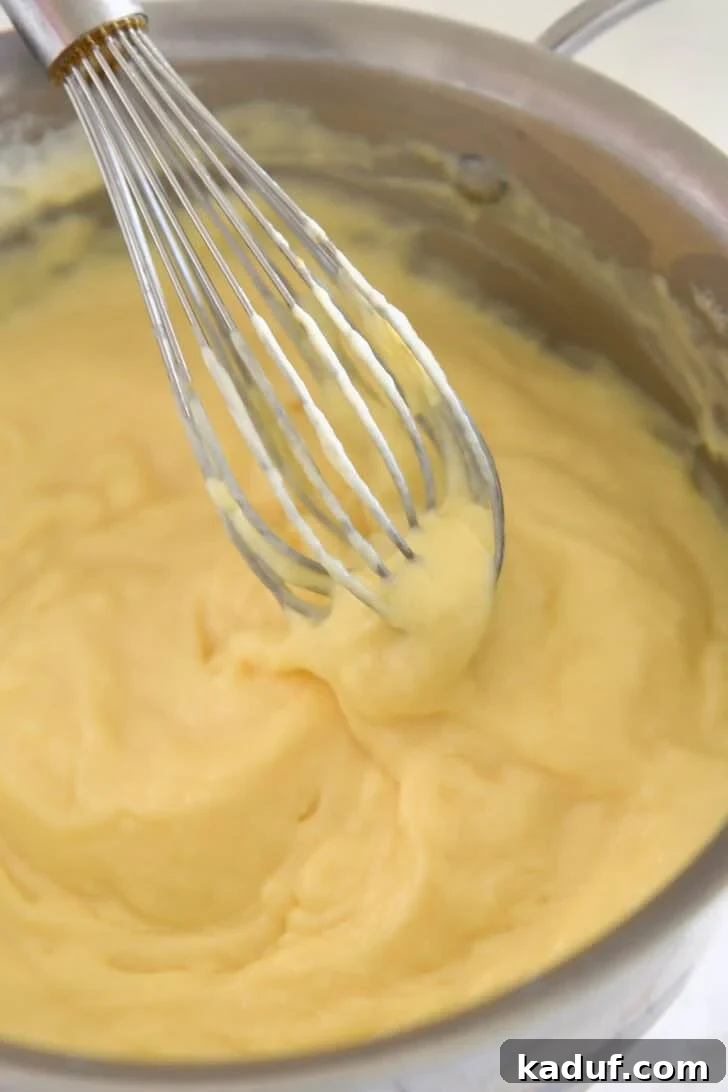 Homemade Banana Pudding from Scratch: Creamy Classic Recipe 6 Whisking thick vanilla pudding with wire whisk in stainless pot.