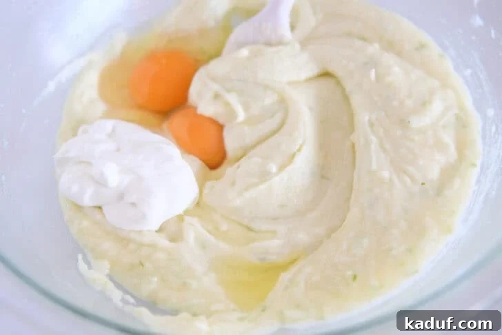 Glass bowl with mixed butter, lime zest, sugar, eggs, oil and sour cream.